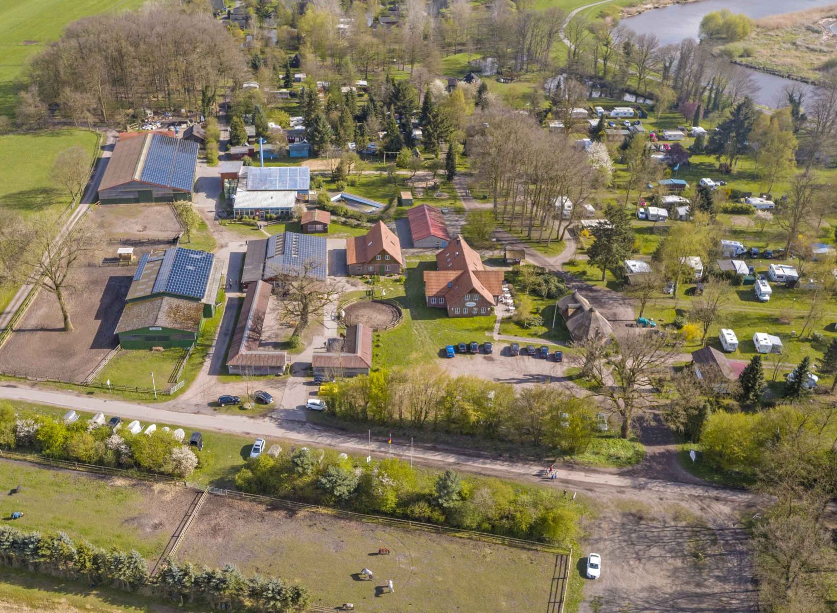Luftaufnahme des Campingplatzes im Ferienpark Geesthof mit Wohnwagen- und Zeltstellplätzen in grüner Wald- und Wiesenlandschaft