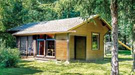 Modernes eingeschossiges Ferienhaus aus Holz mit großen Glasfronten, kleiner Terrasse und Waldblick