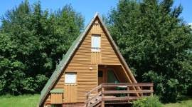 A-förmiges Holzferienhaus im Schatten unter Bäumen im Geesthof Ferienpark