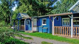 Reihe blauer Holzferienhäuser mit Veranda im Geesthof Ferienpark