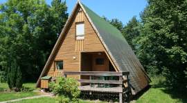 A-förmiges Holzferienhaus im Schatten unter Bäumen im Geesthof Ferienpark