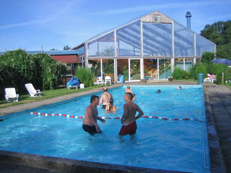 Foto des Freibads mit einem Becken und Liegestühlen auf der nebenliegenden Wiese.
