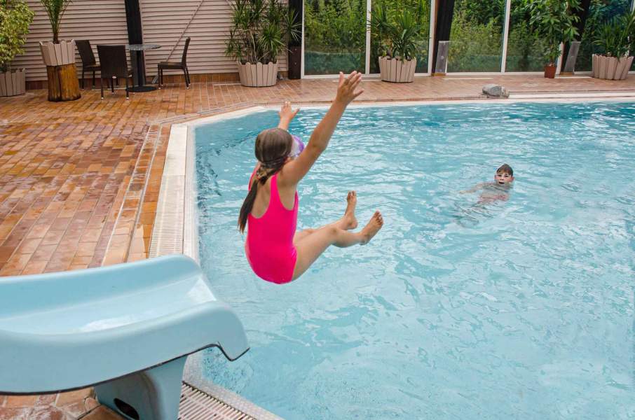 Foto eines Mädchens, das von einer Wasserrutsche in ein Schwimmbecken rutscht.