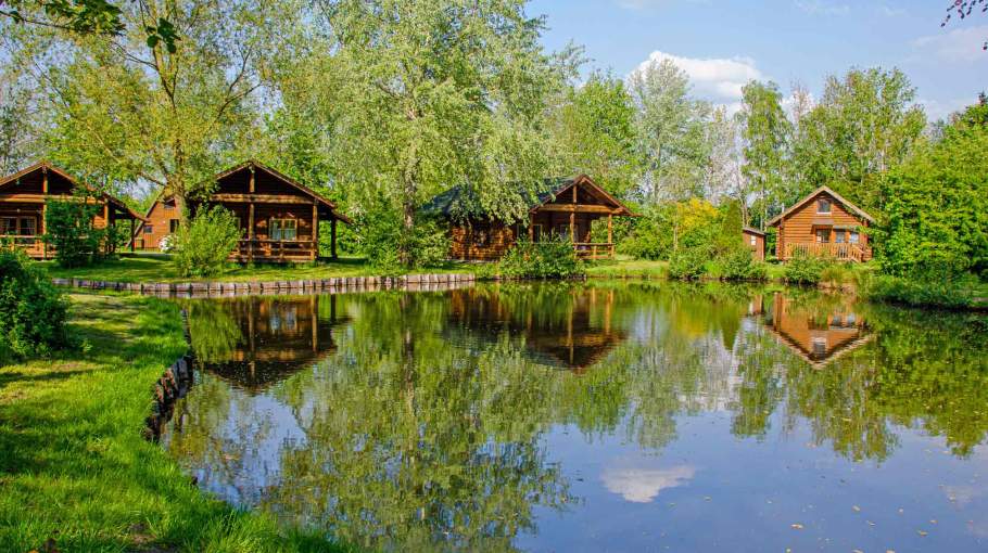 Foto von Holzferienhäusern, die an einem Ententeichen stehen.