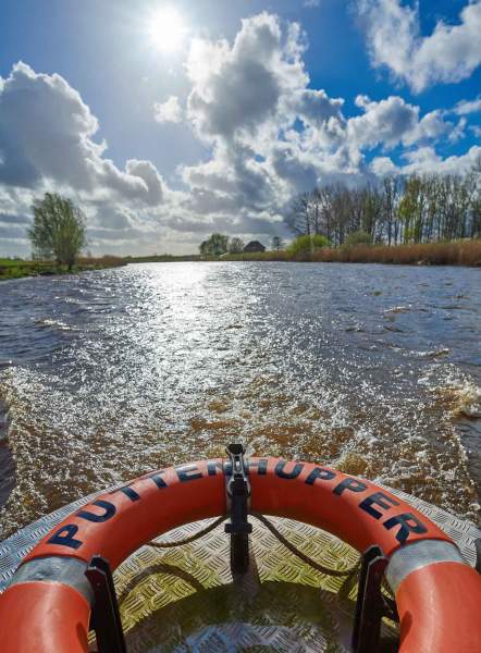 Foto des Rettungsring, der am Heck vom Püttenhüpper befestigt ist mit Ausblick auf die Oste.