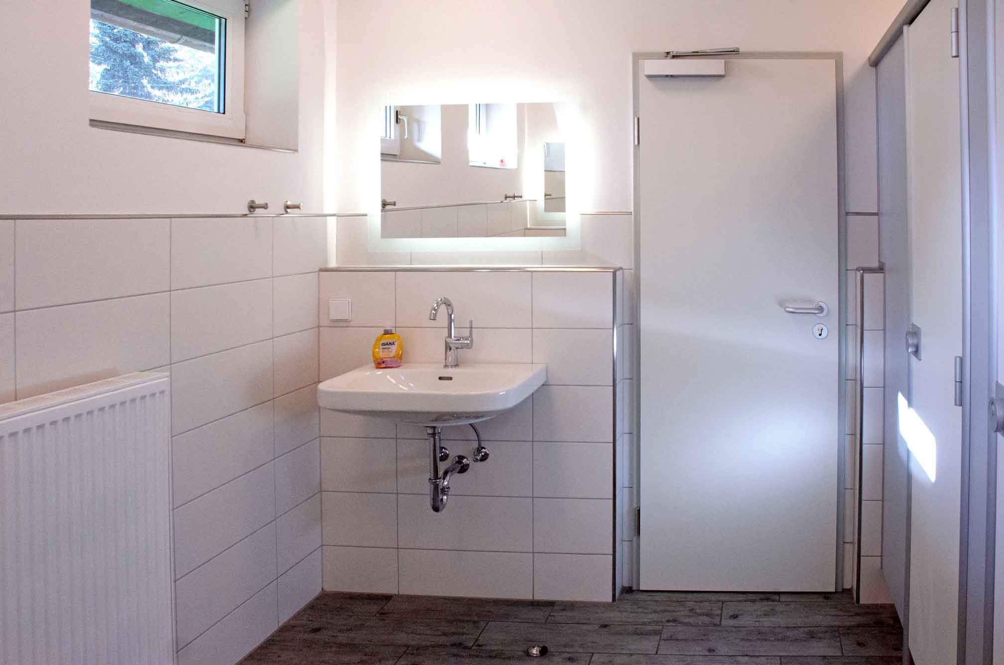 Foto von dem Duschbereich im grünen Sanitärgebäude mit Duschen und Waschbecken.