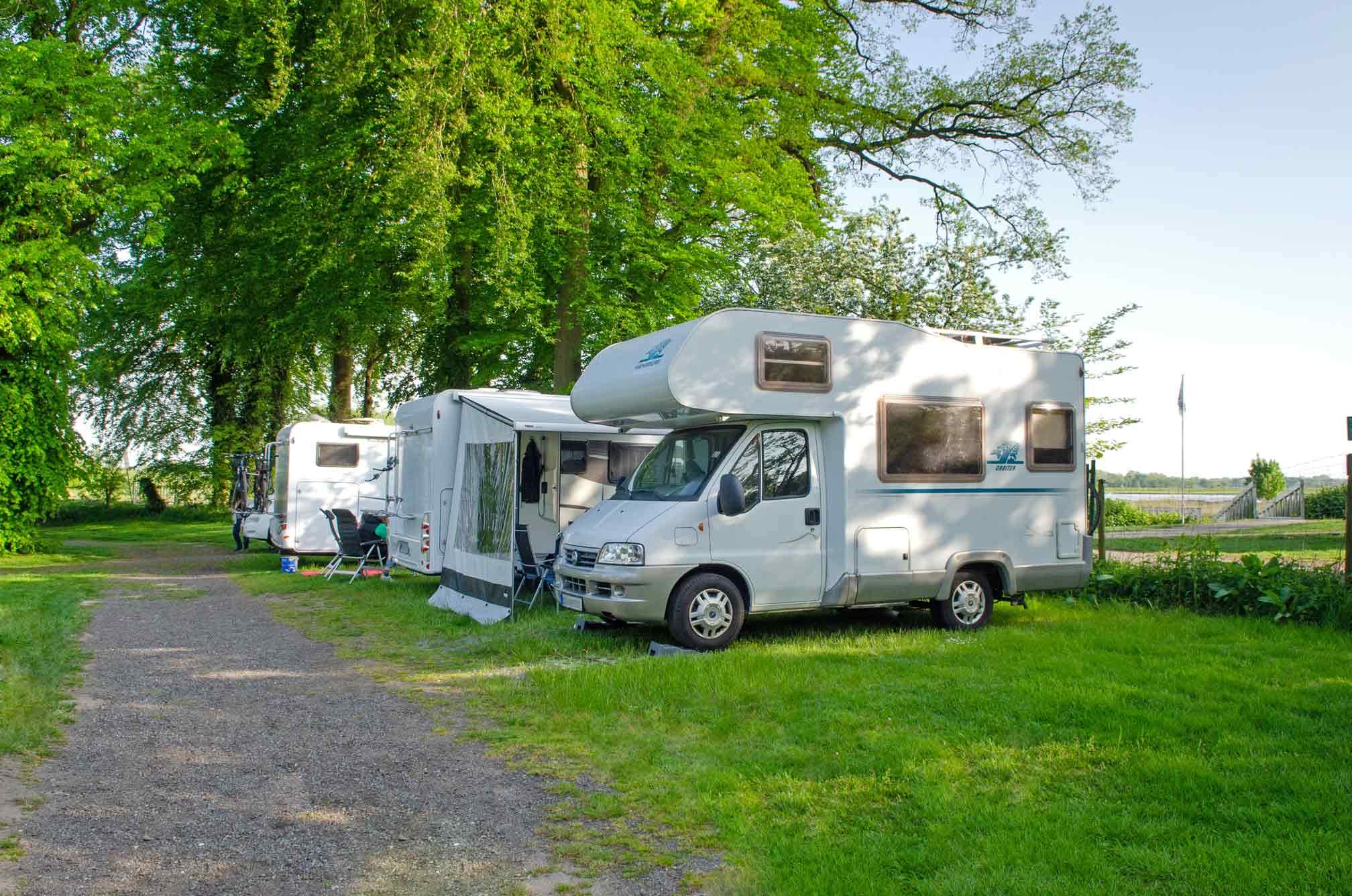 Foto von Stellplätzen, die direkt an der Oste liegen, auf denen Wohnmobile stehen.