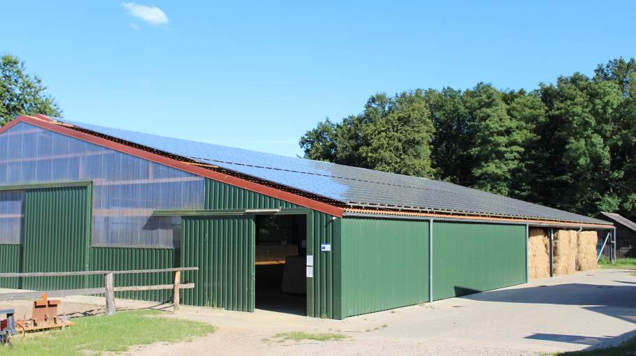 Foto von der Reithalle mit Solaranlagen und Strohlager.