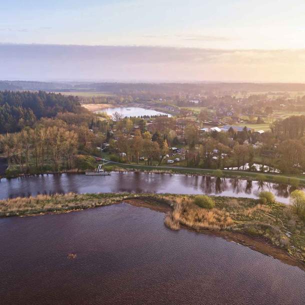 Der Fluss Oste mit Bäumen am Ufer und dem Ferienpark Geesthof im Hintergrund