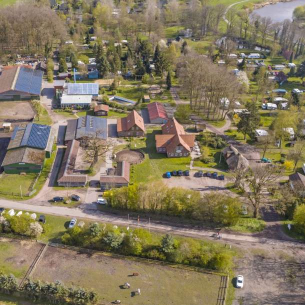 Luftaufnahme einer Reithalle und eines Pferdestalls mit Solaranlagen auf den Dächern.