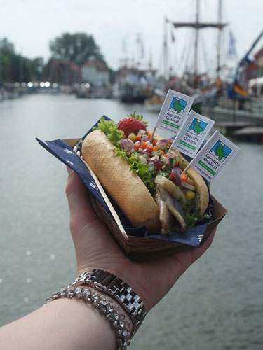 Foto von einem Fischbrötchen, das vor die Kamera gehalten wird.