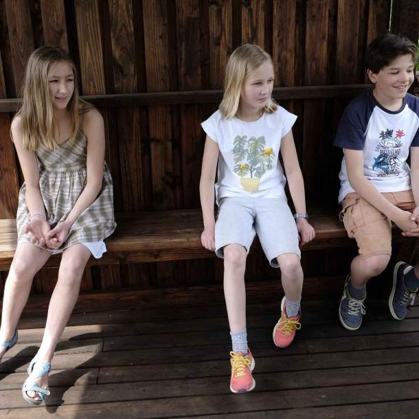 Foto von drei Kindern, die auf einer Holzbank sitzen