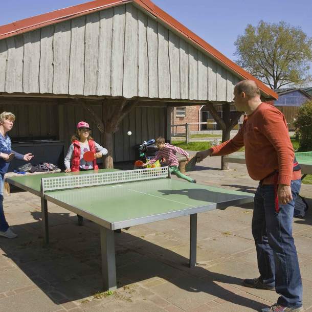Foto einer Gruppe von Menschen, die an einer Tischtennisplatt spielen.