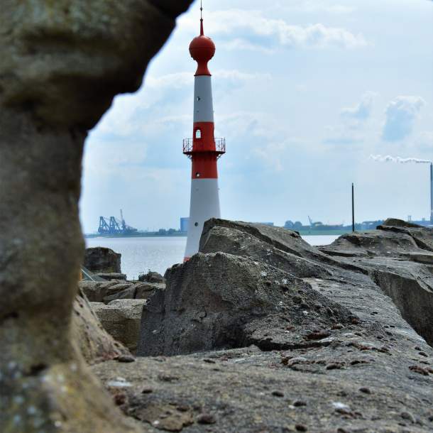 Foto von einem Leuchtturm hinter Felsvorsprüngen.