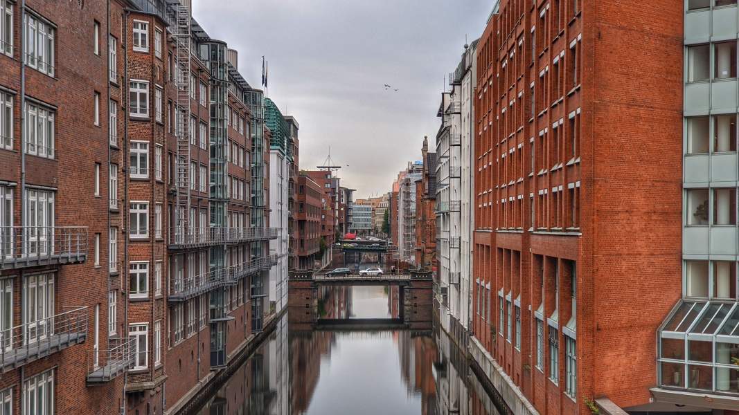 Das Bild zeigt die Speicherstadt von Hamburg, wo das Wasser mitten durch hohe Häuser fließt.