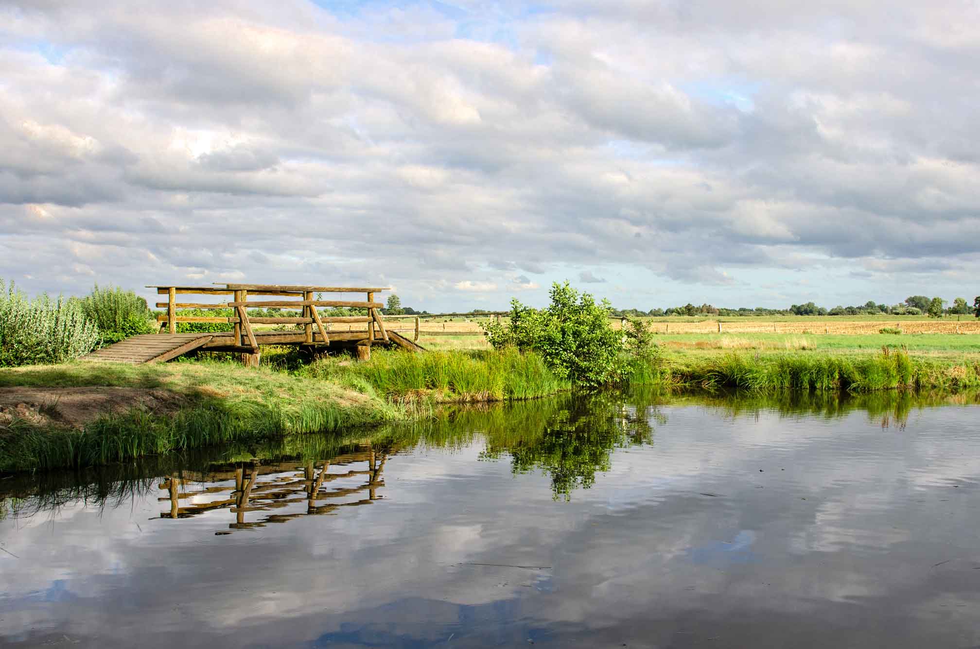 Foto des Forellenteiches mit bewölktem Himmel und weiter Landschaft.