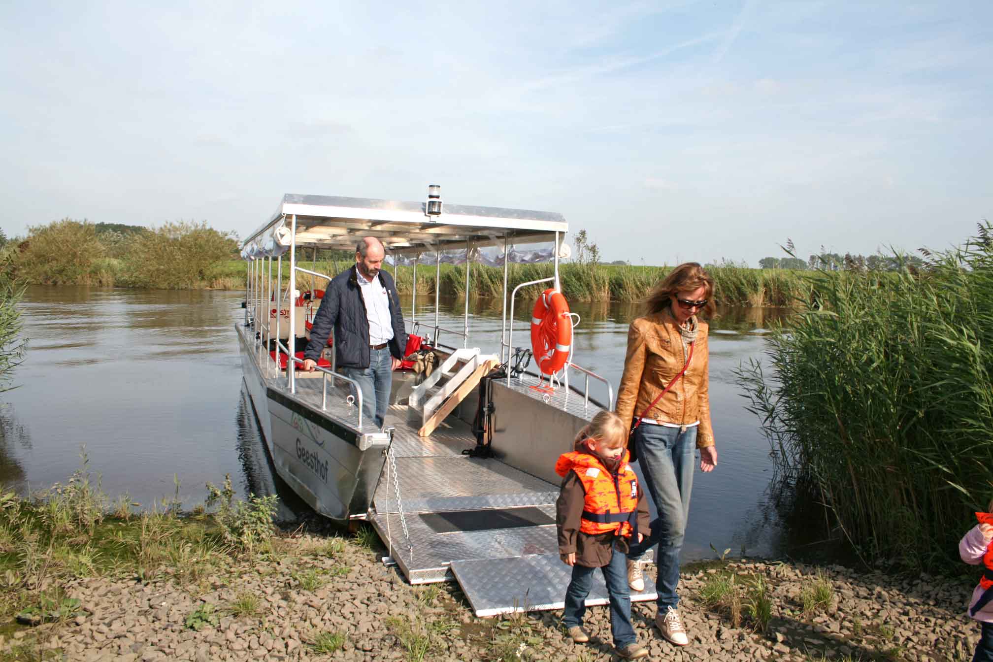 Foto von drei Personen, die vom Püttenhüpper Ausflugsboot an Land gehen. 