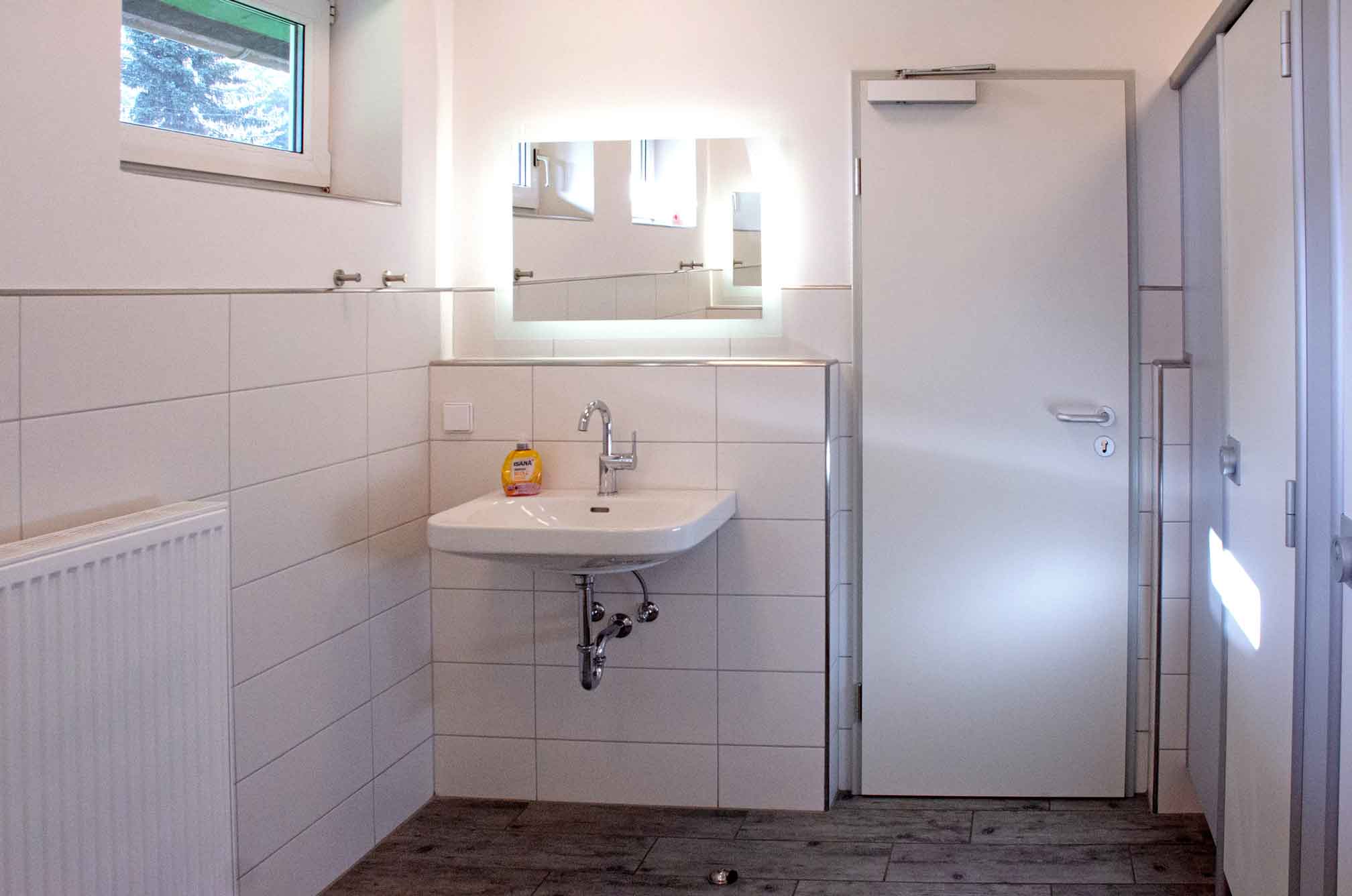 Foto von dem Duschbereich im grünen Sanitärgebäude mit Duschen und Waschbecken.