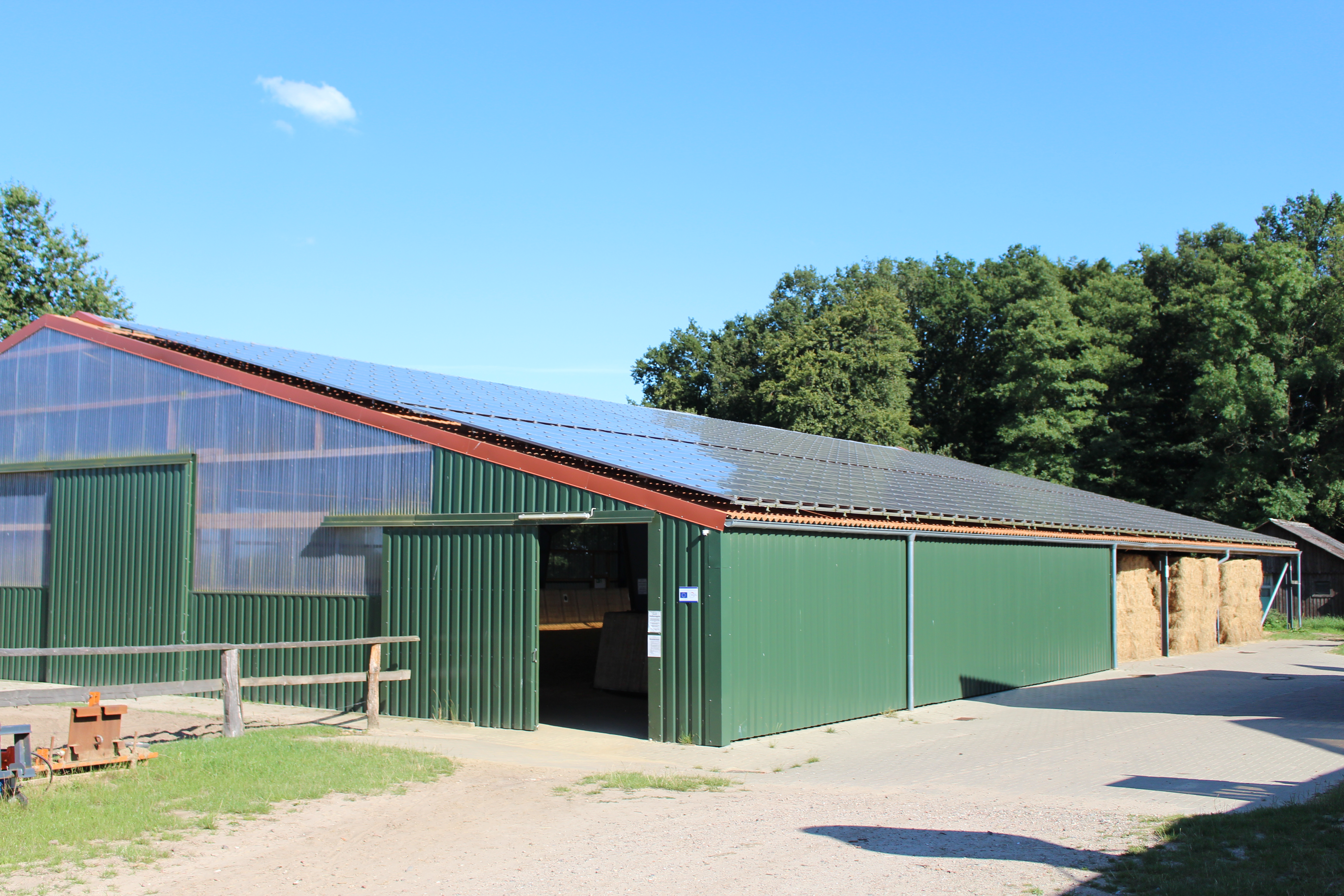 Foto von der Reithalle mit Solaranlagen und Strohlager.