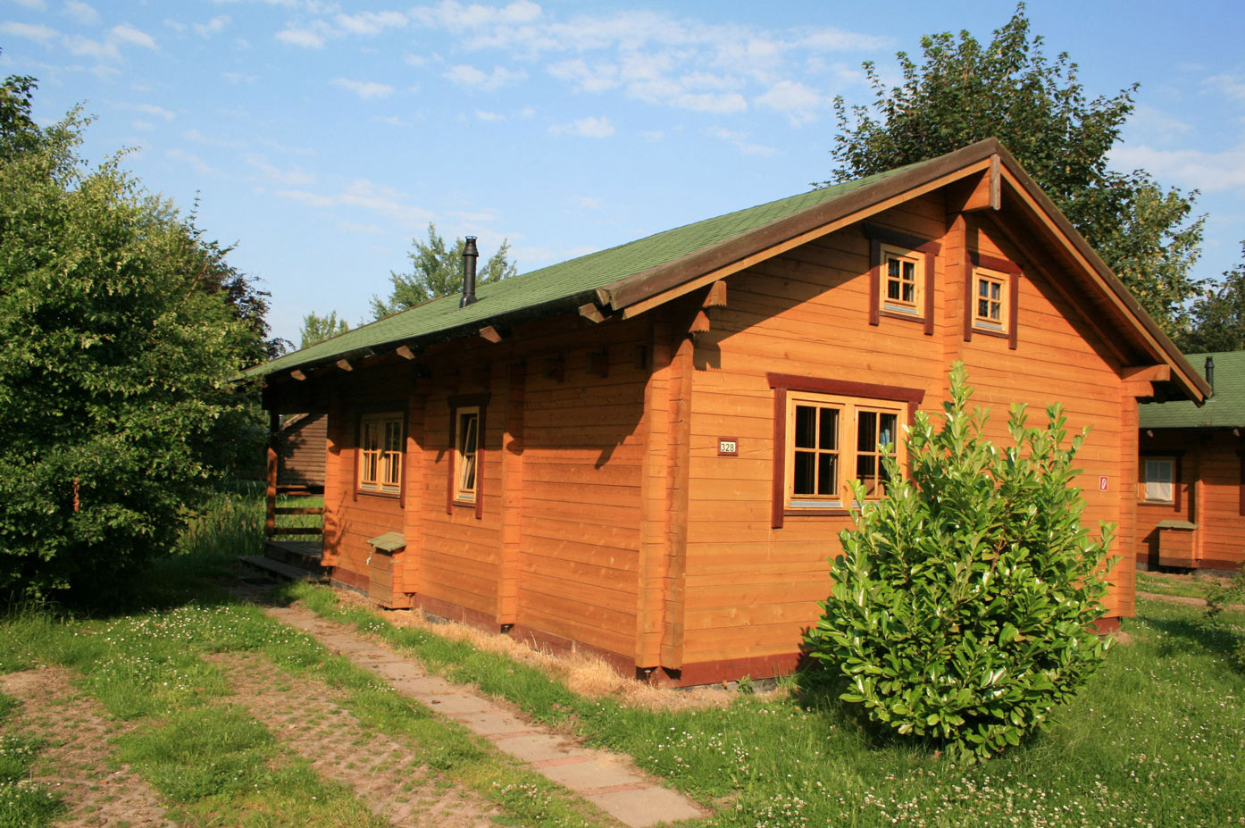 Typ D – Blockhaus 328 mit zwei Etagen, Fensterläden und Ziergiebel, auf grüner Wiese gelegen