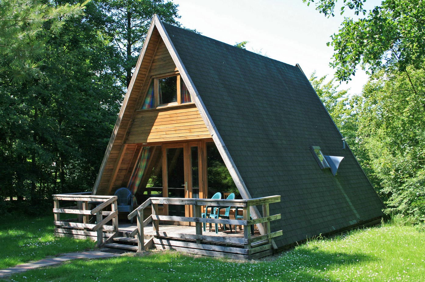 Typ E – Großes Nurdachhaus 302 mit dunklem Dach, Holzveranda und grünem Wiesenbereich