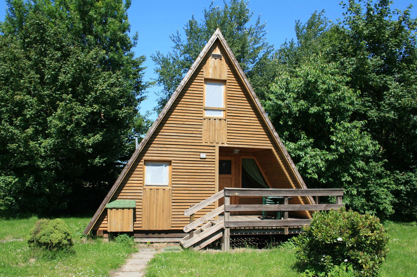 Typ C – Nurdachhaus 313 in spitzem A-Stil mit heller Holzverkleidung und breiter Holzveranda