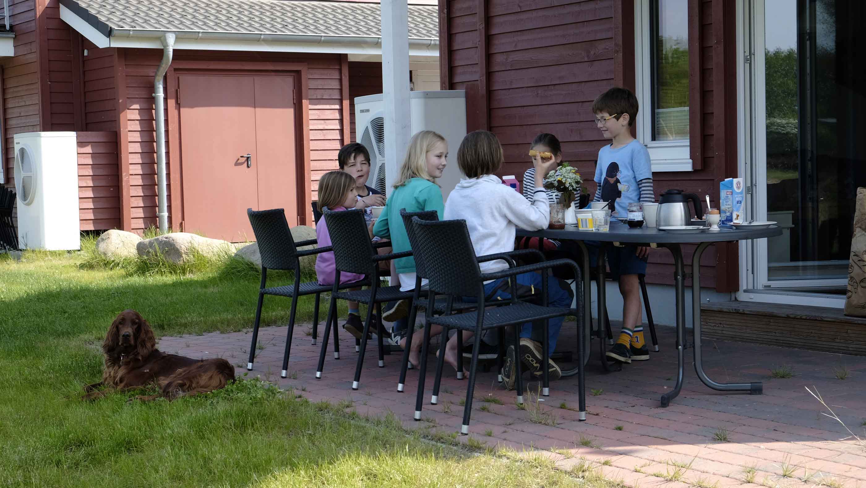 Foto einer Familie, die auf der Terrasse eines Ferienhauses frühstückt.