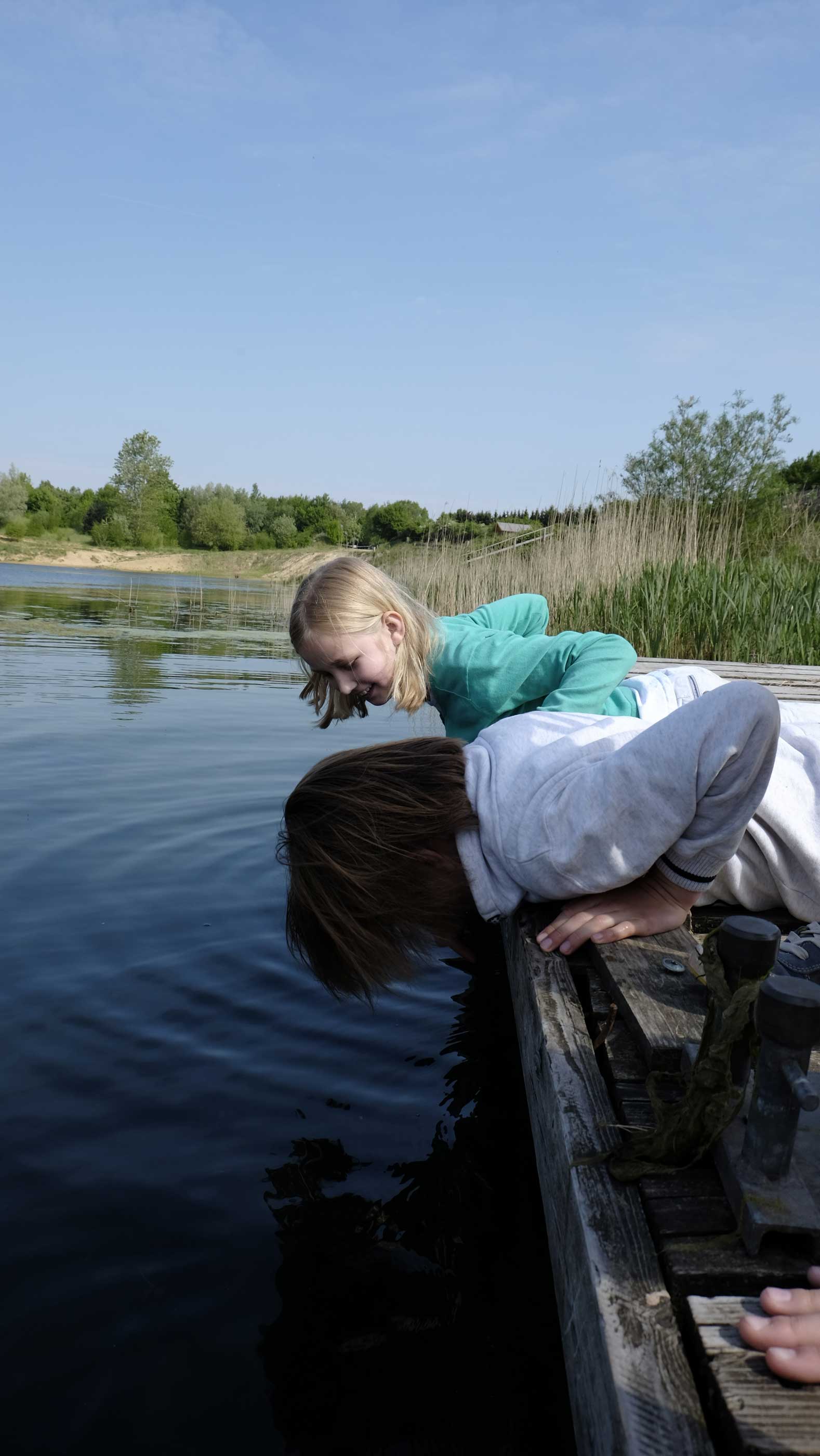 Foto von zwei Kinder, die am Geestsee vom Steg ins Wasser schauen.