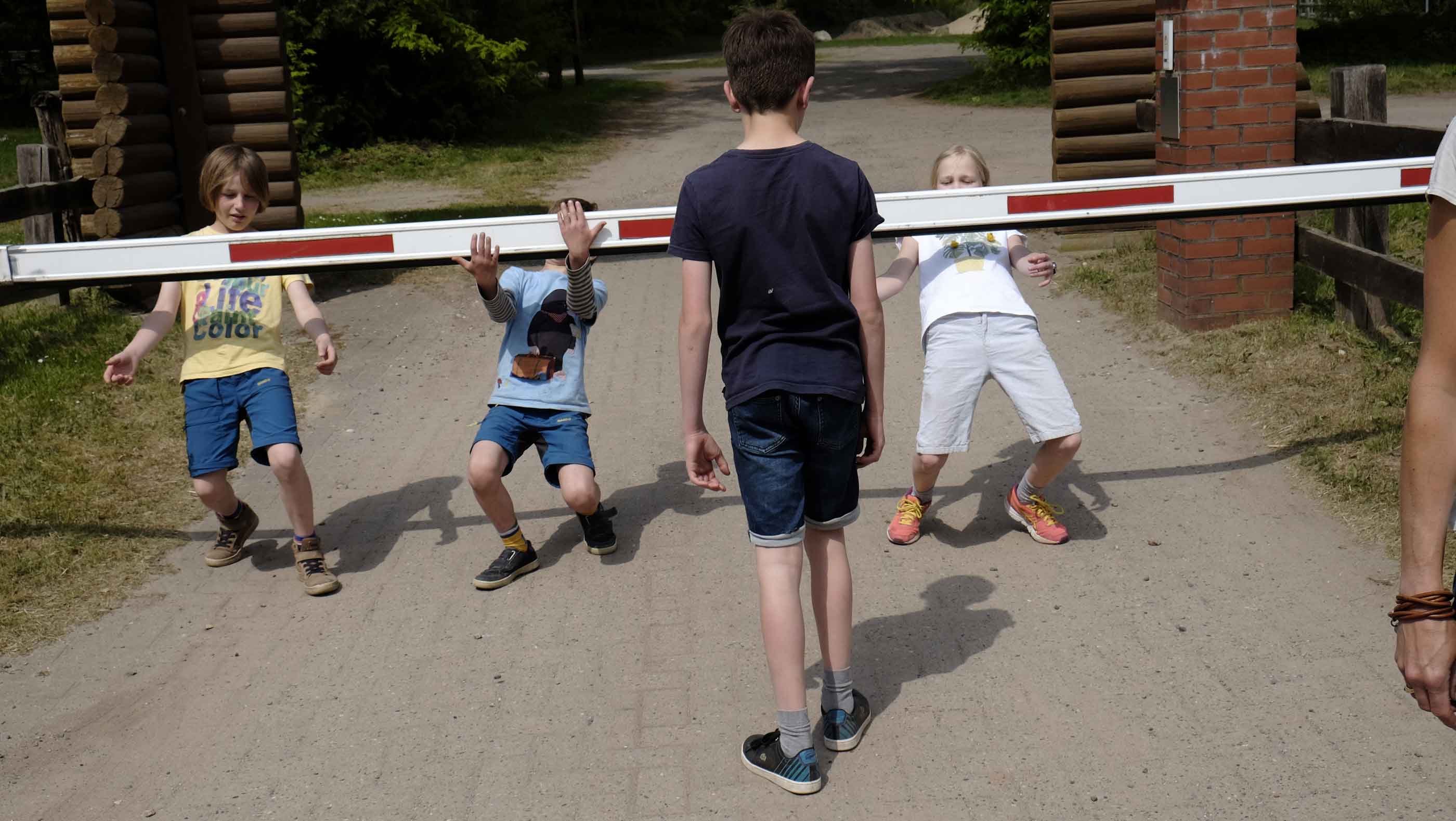 Foto von drei Kindern, die an einer Zufahrts-Schranke spielen.