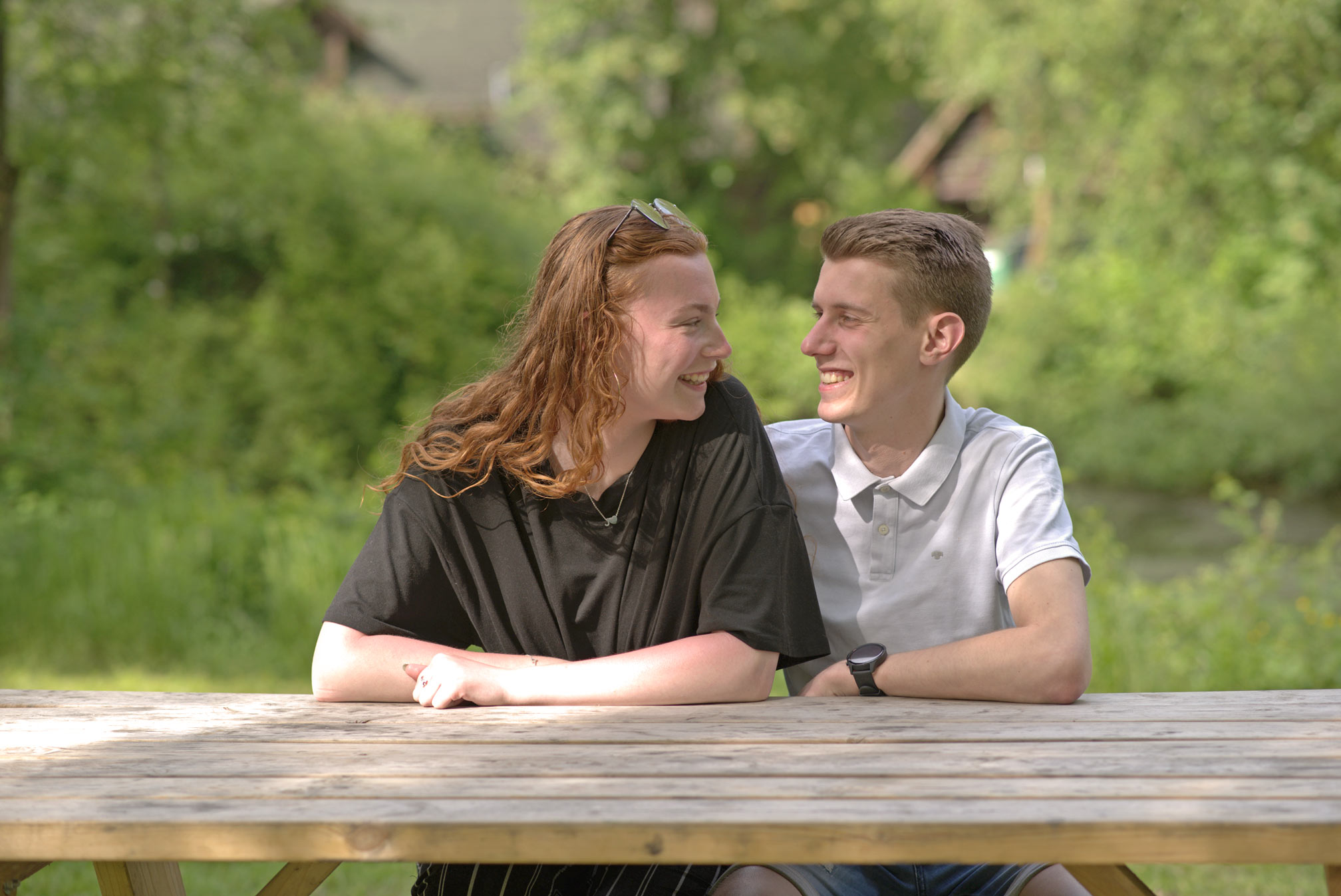 Foto eines jungen Paares, das an einem Holztisch sitzt.