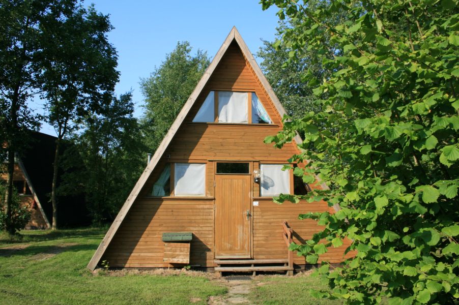Foto von dem Nurdachhaus 378 hinter einem Busch.