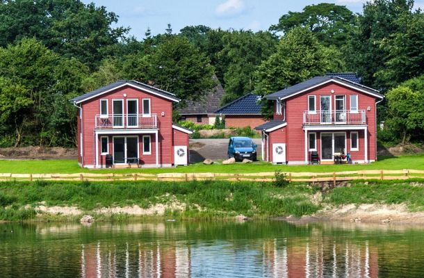 Typ F – Seehaus 407 mit Blick über ruhigen See auf mehrere rote Häuser am Ufer