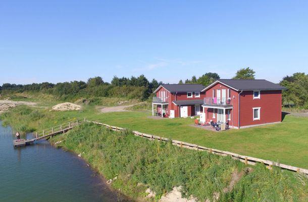 Typ F – Seehaus 409 mit See, Strand und roten Häusern in der Ferne