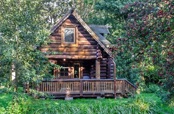 Typ E – karelisches Blockhaus 354 mit Balkon und großem Holzvorbau, inmitten dichter Bäume