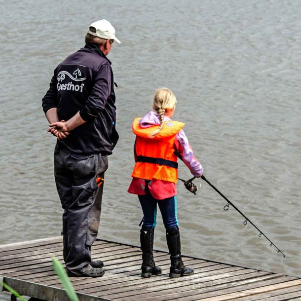 Foto von einem Mädchen und einem Angelguide, die auf einem Steg am Wasser stehen.