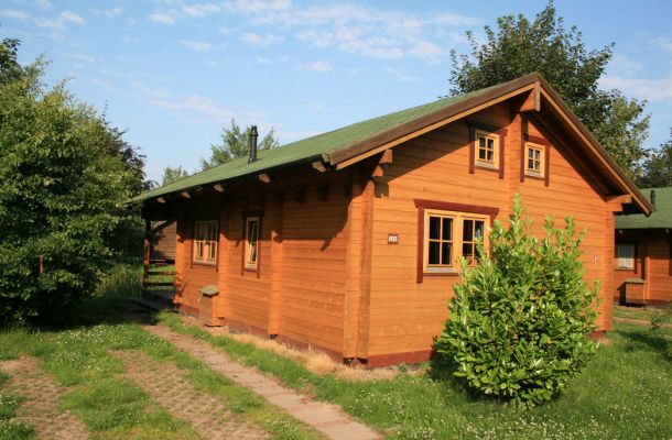 Typ D – Blockhaus 328 mit zwei Etagen, Fensterläden und Ziergiebel, auf grüner Wiese gelegen