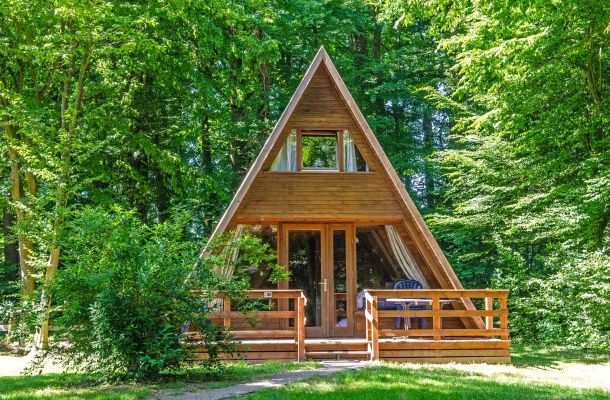 Typ E – Nurdachhaus 306 mit stilvoller Holzverkleidung, Terrasse mit Möbeln und bewaldetem Hintergrund