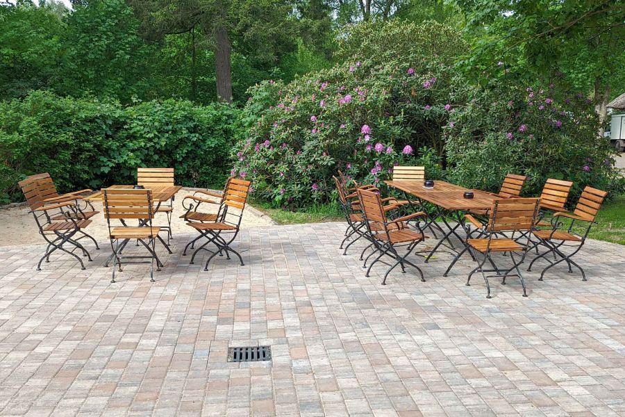 Foto der Holzstühle auf der Restaurant-Terrasse mit Rhododendron.