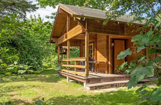 Typ D – Blockhaus 327 im kompakten Stil mit Holzveranda, grünem Gartenbereich und Hecke