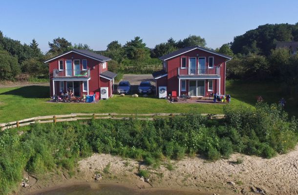 Typ F – Seehaus 401 mit Blick auf zwei rote Doppelhaushälften am Wasser
