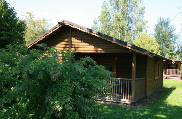 Typ C – Blockhaus 364 mit Veranda, niedriger Bauweise und Bäumen im Hintergrund