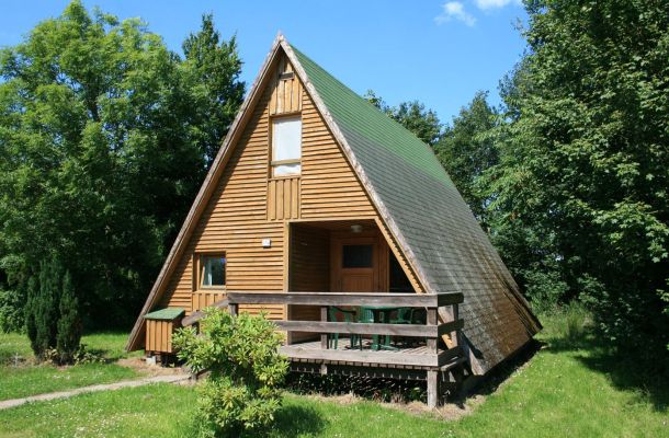 Typ C – Nurdachhaus 312 mit Holzfassade und Terrasse, eingebettet in grüner Wiese vor Bäumen