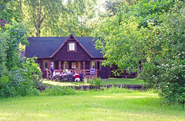 Typ E – karelisches Blockhaus 344 mit Naturdach und massiven Holzstämmen, umgeben von Wiese