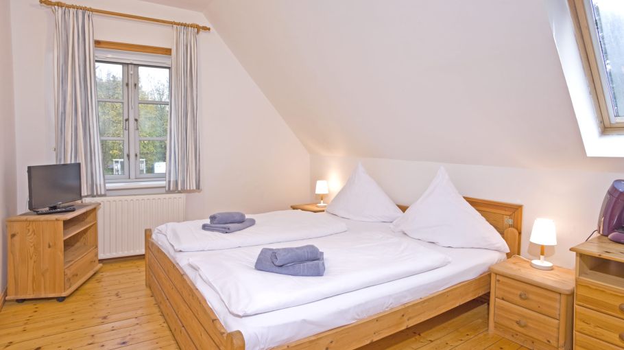 Foto eines Ferienzimmers mit Doppelbett, kleinem Fernseher und Schreibtisch