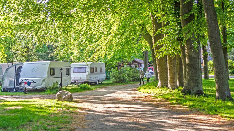 Foto eines Campingplatzes mit Wohnwagen und Vorzelten an einem Weg
