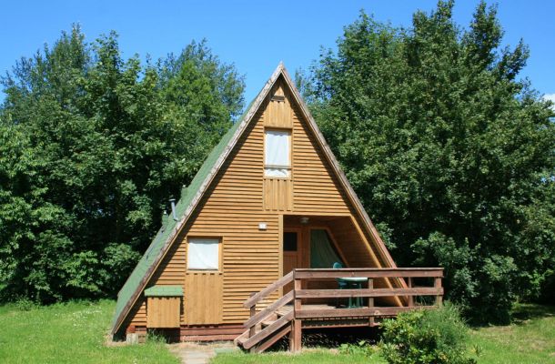 Typ C – Nurdachhaus 314 mit Fensterfront, Holzterrasse und dichter Bepflanzung drumherum