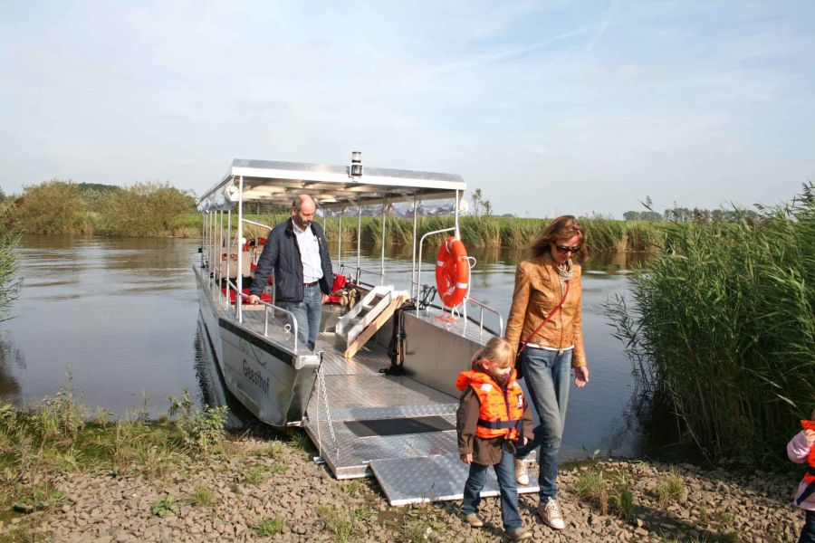 Foto von drei Personen, die vom Püttenhüpper Ausflugsboot an Land gehen. 