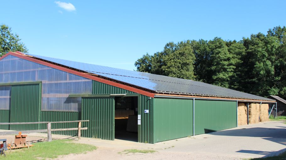 Foto von der Reithalle mit Solaranlagen und Strohlager.