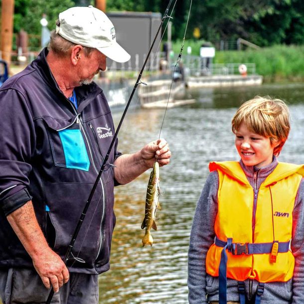 Foto von einem Jungen und dem Angelguide, die einen Hechtköder anschauen.