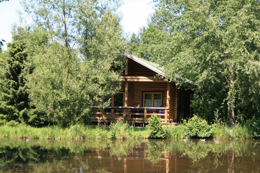 Foto von dem Blockhaus 330 zwischen Bäumen am Wasser.